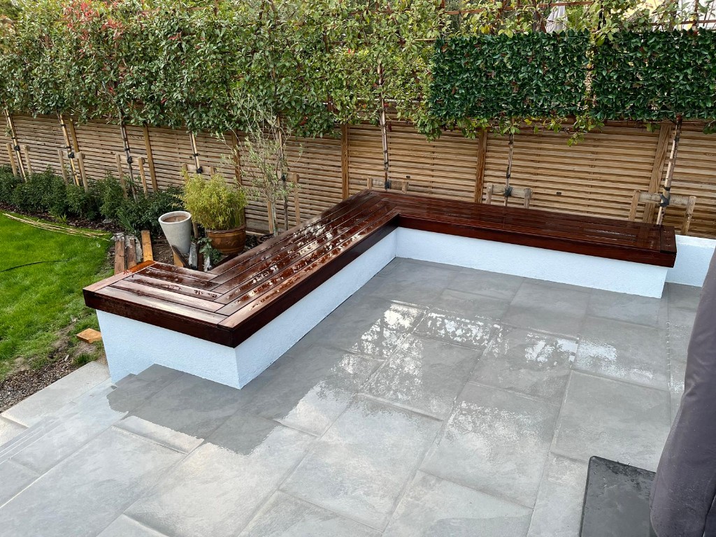 Stone patio with grey garden studio, dark stained fence and warm outdoor string lights