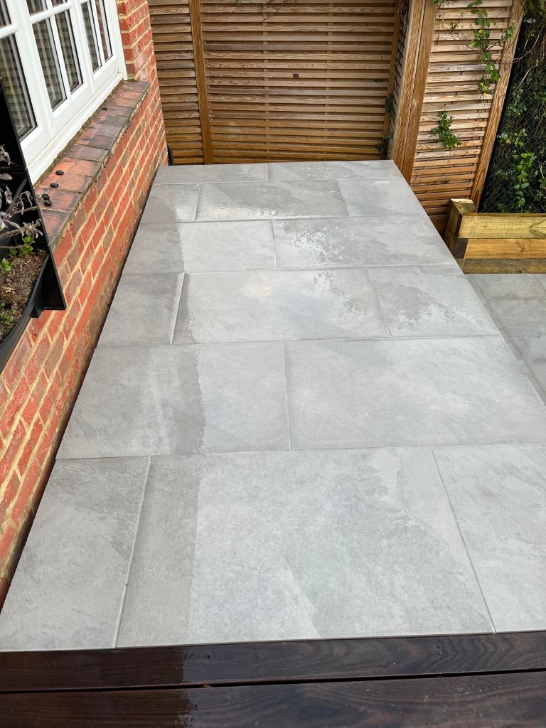 Light grey stone patio beside traditional brickwork with modern timber slat screening
