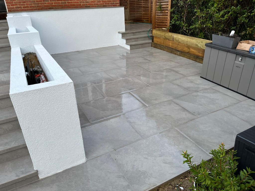 Grey paved upper terrace with crisp white rendered walls facing timber fencing
