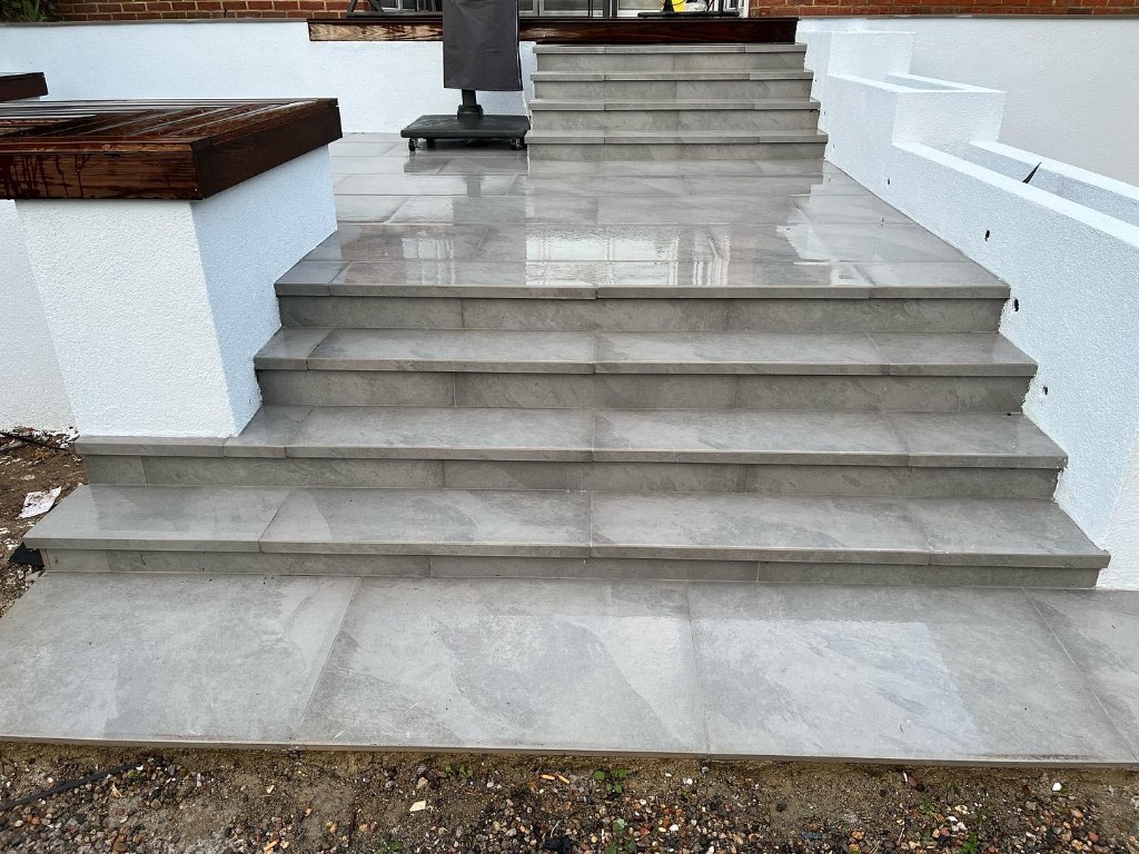 Wide grey porcelain or stone steps with white rendered walls and timber bench capping