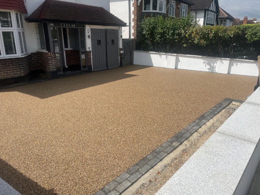 Resin-bound driveway surfacing at a residential front entrance with tan aggregate and charcoal block edging